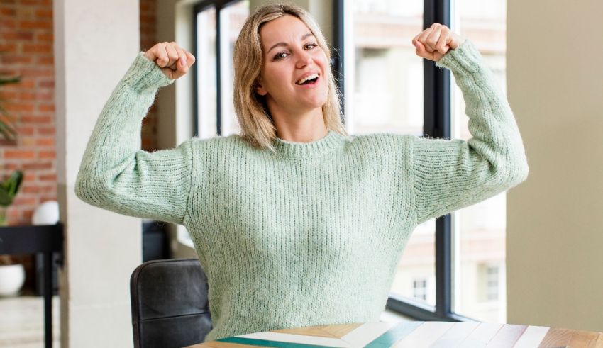 A woman is flexing her muscles in front of a window.