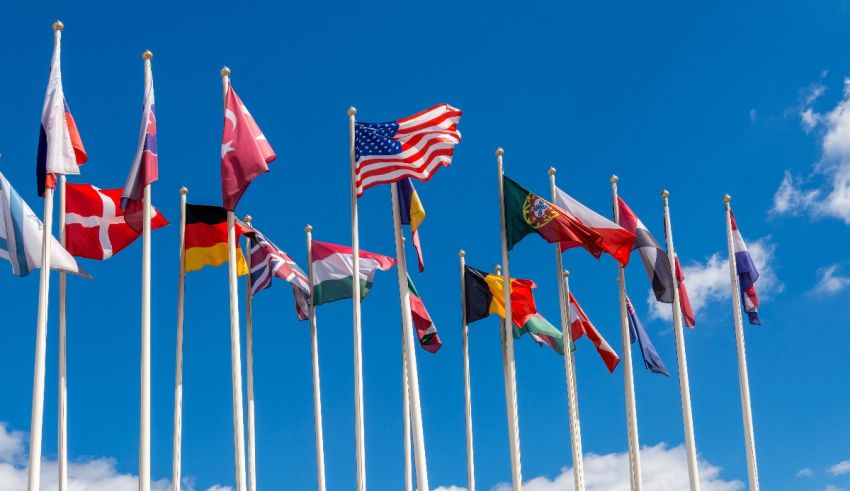 A group of flags flying in front of a blue sky.
