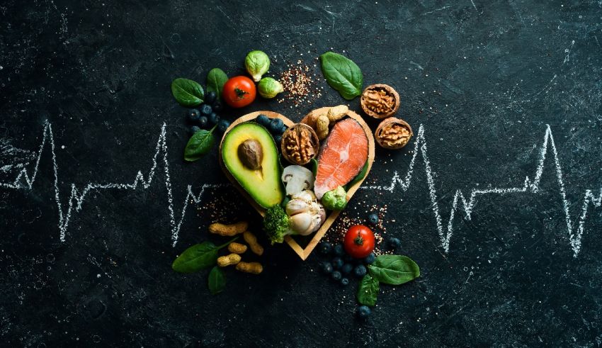 A heart shaped heart with fruits, vegetables and nuts on a black background.
