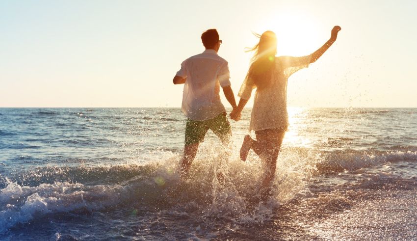 A man and woman are running in the water at the beach.