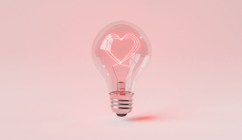 A light bulb with a heart in it on a pink background.