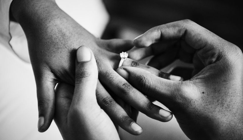 A black and white photo of a man putting a wedding ring on a woman's hand.
