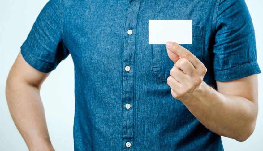 A man is holding up a blank business card.