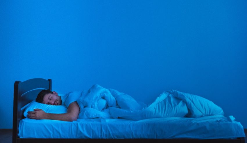 A man is sleeping on a bed in a blue room.