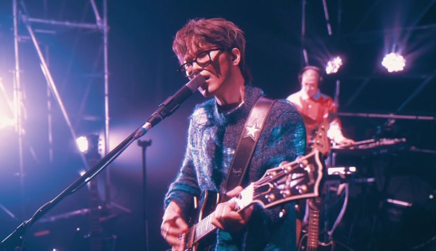 A man playing a guitar in front of a microphone.