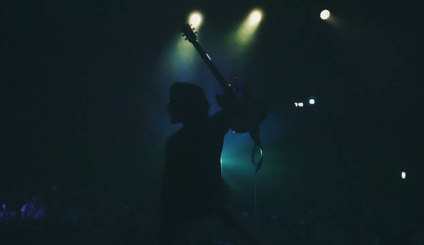 A silhouette of a person playing a guitar at a concert.