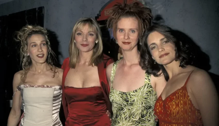 Four women posing for a picture in a red dress.