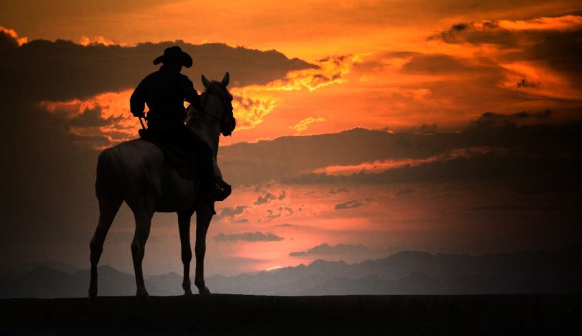 A cowboy riding a horse at sunset.