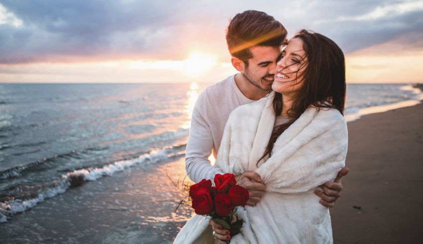 A couple hugging on the beach at sunset.