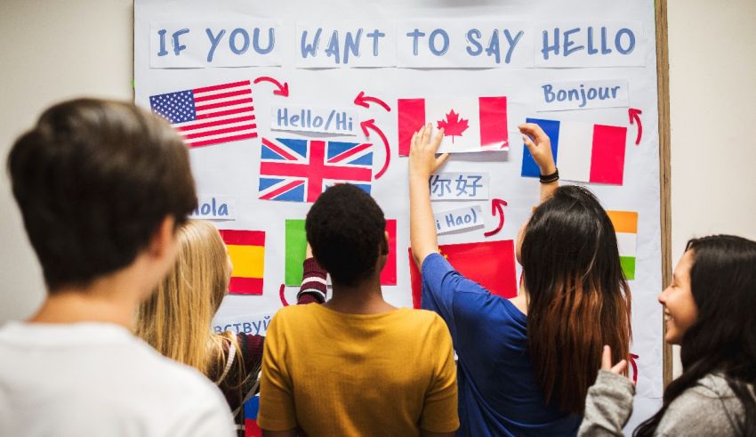 A group of people standing in front of a board that says is there a language you want to learn?.