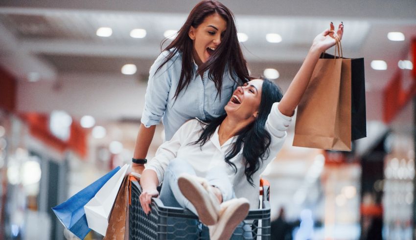 Two women shopping in a shopping mall with shopping bags.