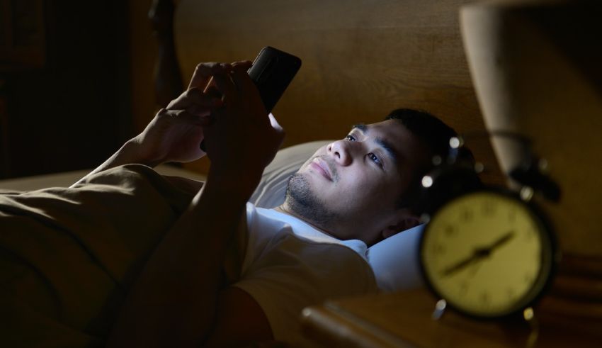 A man laying in bed looking at his phone.