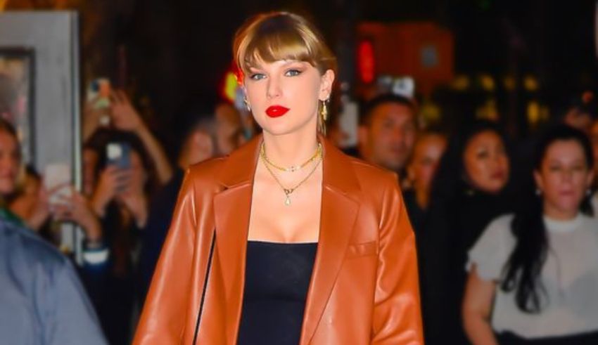 Taylor swift is walking down the street in a brown outfit.