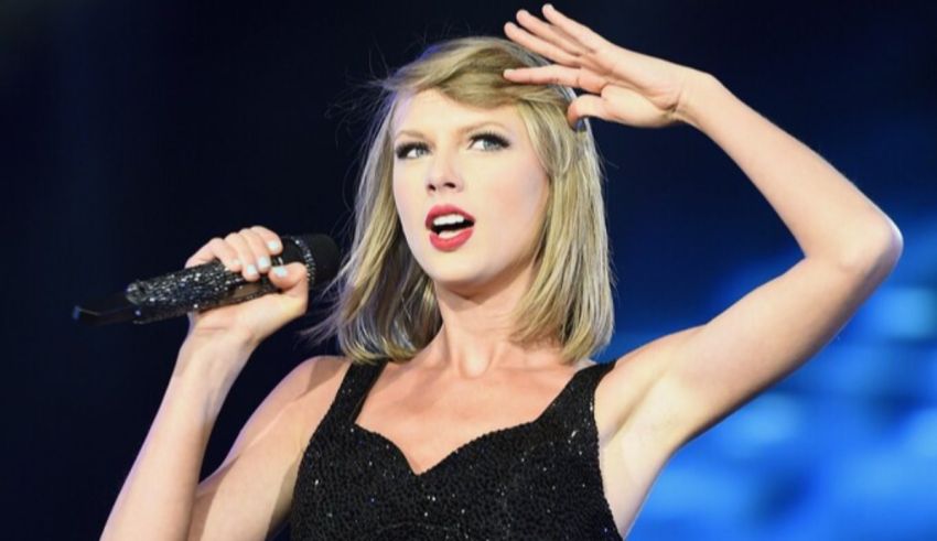 Taylor swift performs on stage in a black dress.