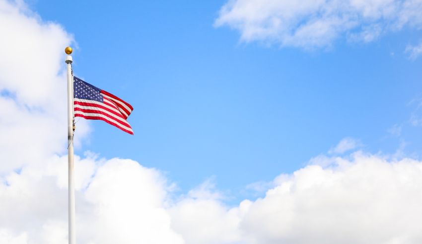 An american flag flies in the wind against a blue sky.