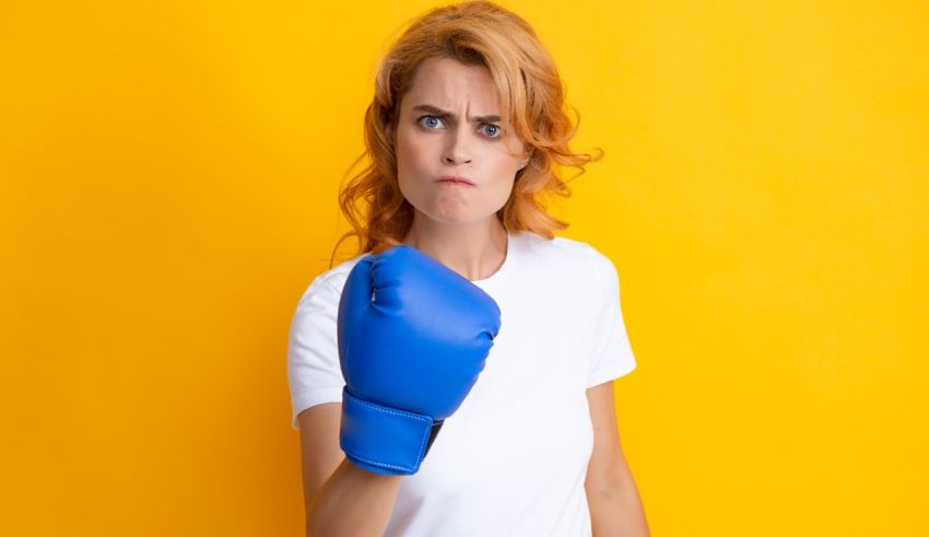 A woman with blue boxing gloves on a yellow background.