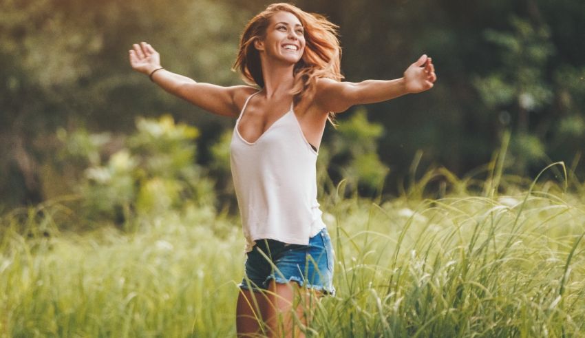 A woman is standing in a field with her arms outstretched.