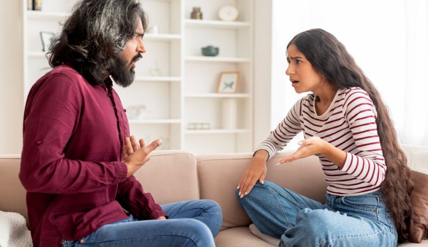 A man and woman sitting on a couch talking to each other.