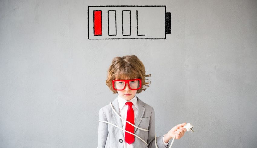 A young boy in a suit with glasses and a charger in front of him.