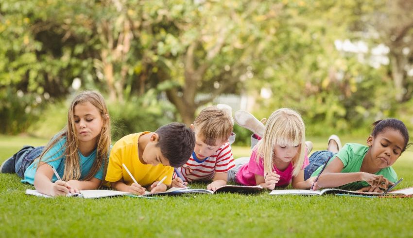 A group of children laying on the grass and writing.