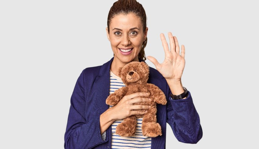 A woman holding a teddy bear and making a stop sign.