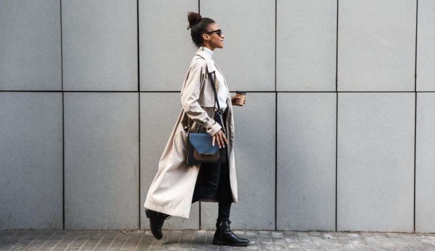 A woman in a trench coat walking down a sidewalk.