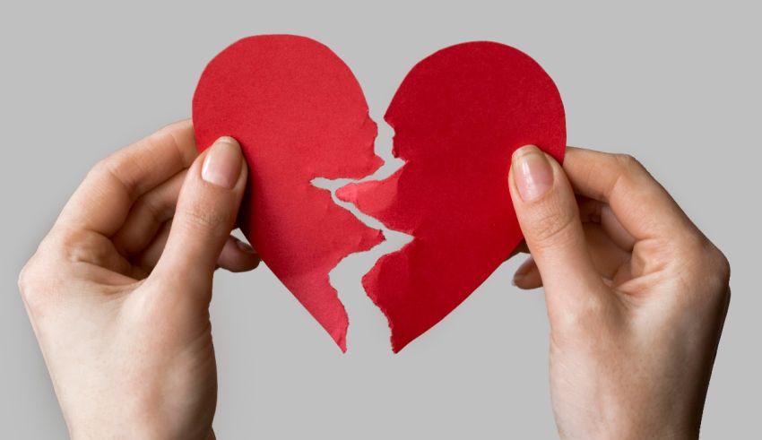 A pair of hands holding a broken red heart.