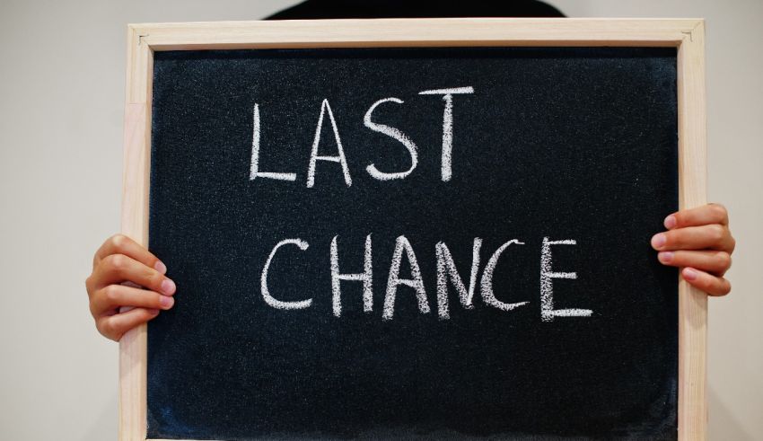 A person holding up a chalkboard with the word last chance.