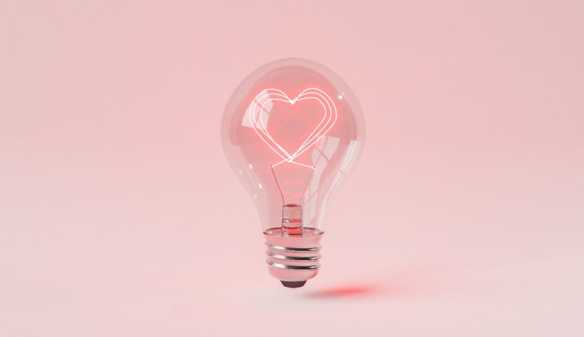 A light bulb with a heart in it on a pink background.