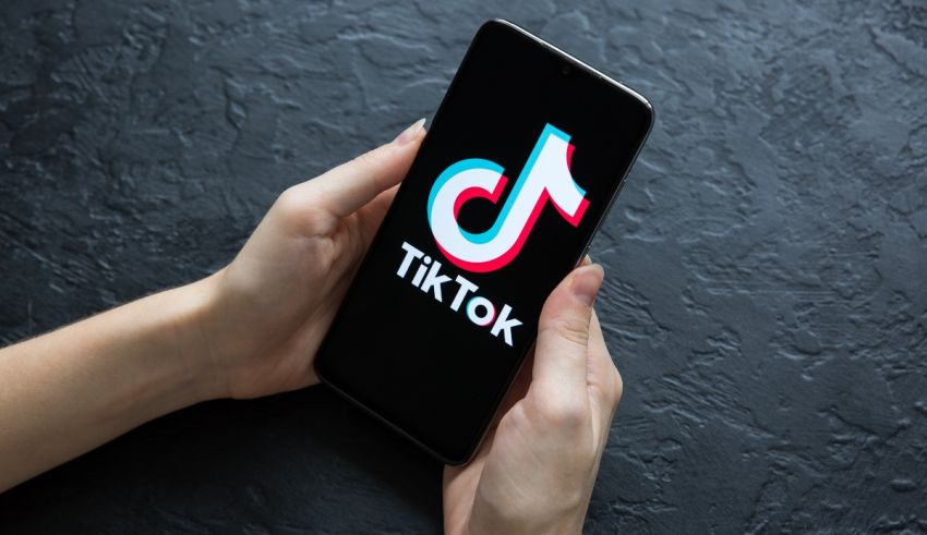 A person holding a phone with the tiktok logo on it.