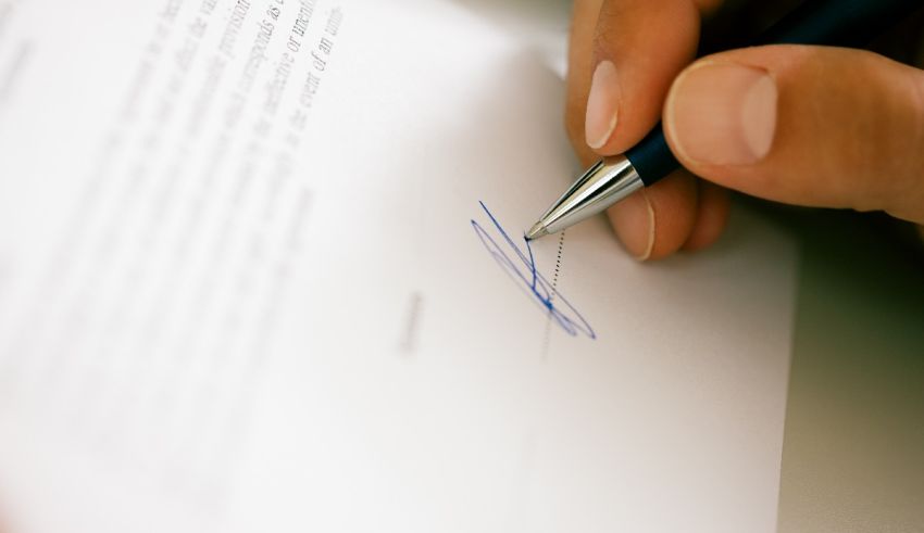 A person signing a document with a pen.