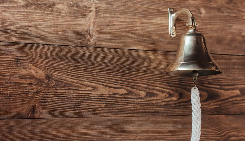 A bell hanging on a wooden wall.