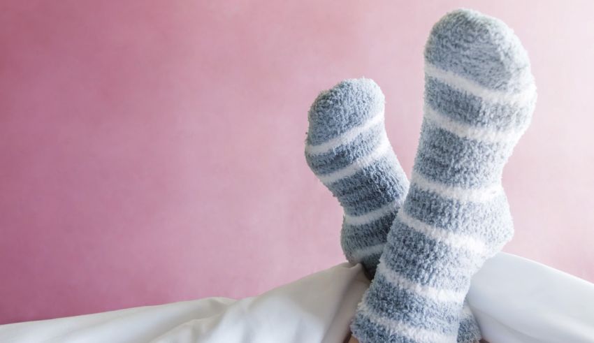 A woman's feet are laying on a bed with socks on.