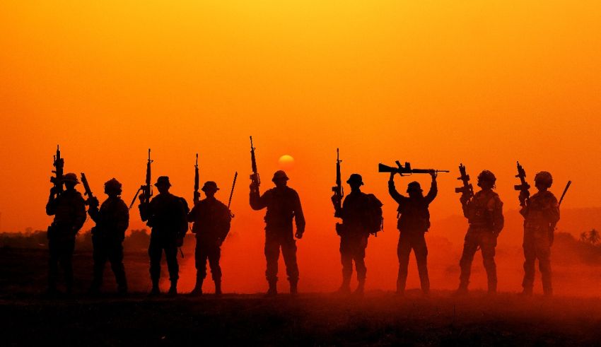 Silhouettes of soldiers holding rifles at sunset.