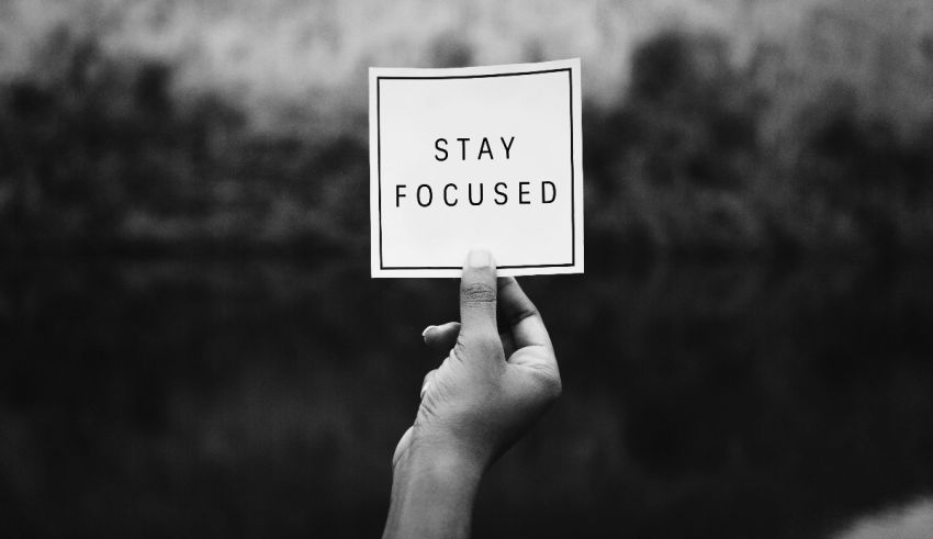 A hand holding up a sign that says stay focused.