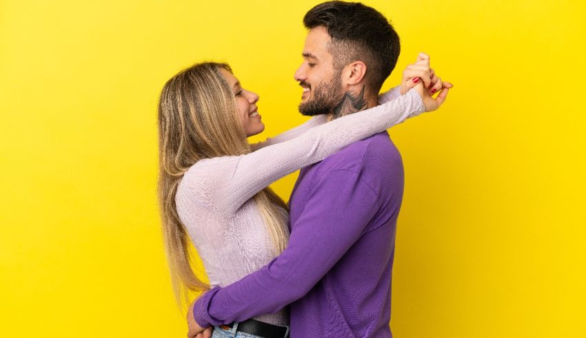 A young man and woman hugging against a yellow background.