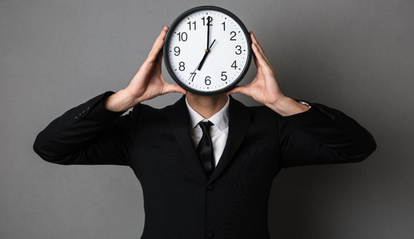 A man in a suit covering his face with a clock.