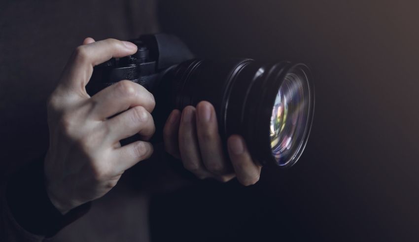 A person holding a camera on a dark background.