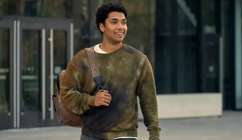 A young man walking down the street with a backpack.