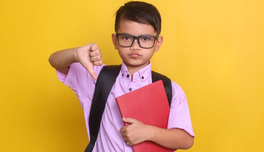 A boy wearing glasses and holding a red folder with a thumbs down sign.