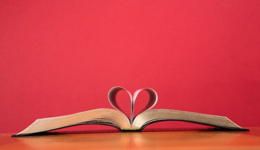 An open book with a heart cut out of it on a red background.