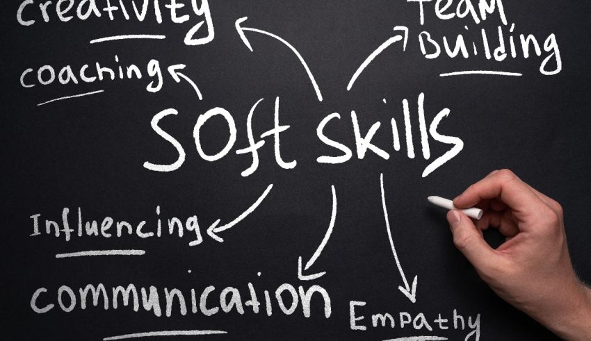 A hand writing the word soft skills on a blackboard.