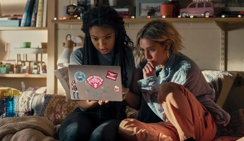 Two women sitting on a couch looking at a laptop.