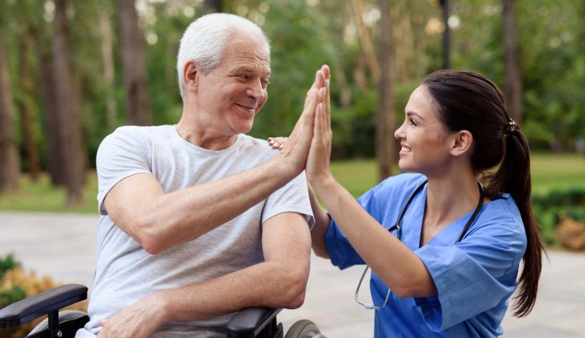 A nurse giving a high five to an elderly man in a wheelchair.