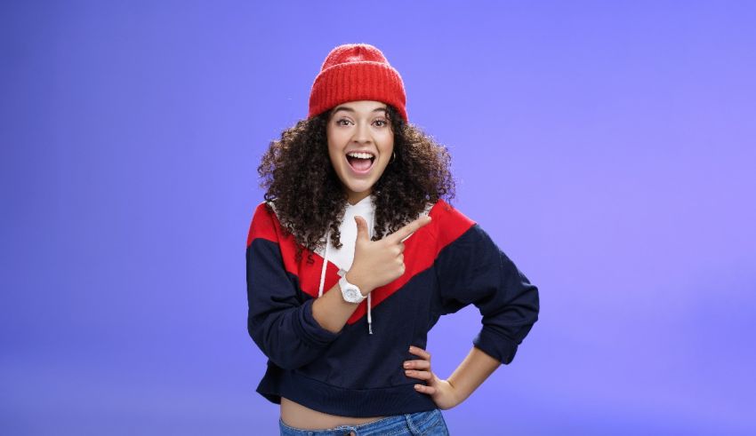 A young woman wearing a red beanie and jeans posing for the camera.