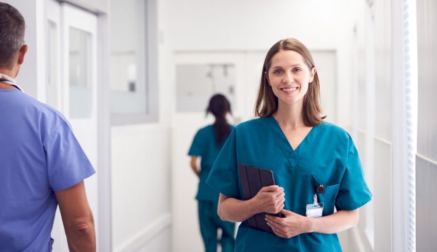 A nurse is walking down a hallway with a clipboard.
