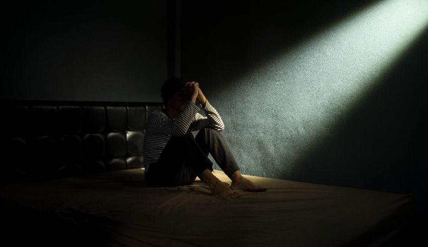 A man sitting on a bed with a light shining on him.