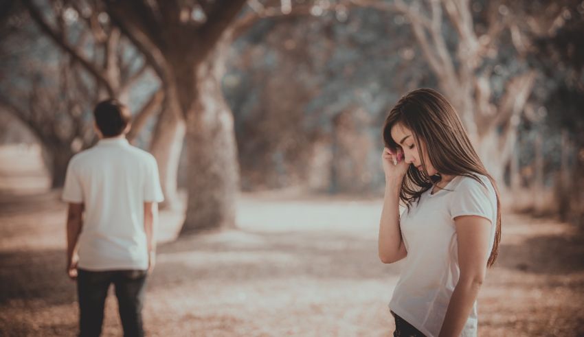 A man and woman standing in a park looking at each other.