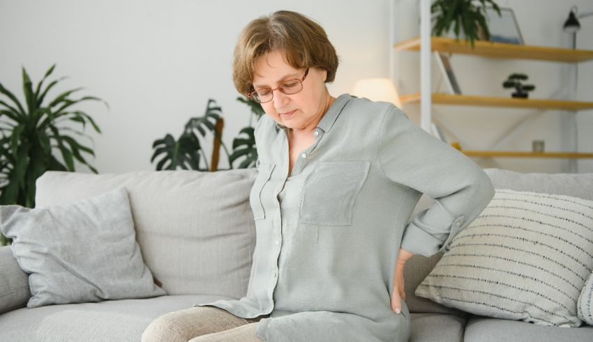 A woman with back pain sitting on a couch.