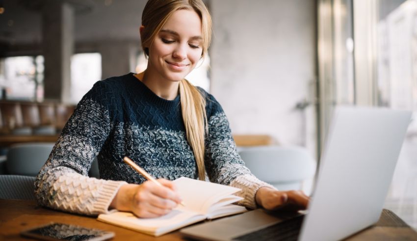 A woman sitting at a table with a laptop and a pen.